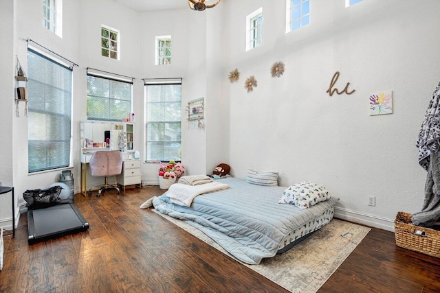 bedroom with a high ceiling and dark hardwood / wood-style floors