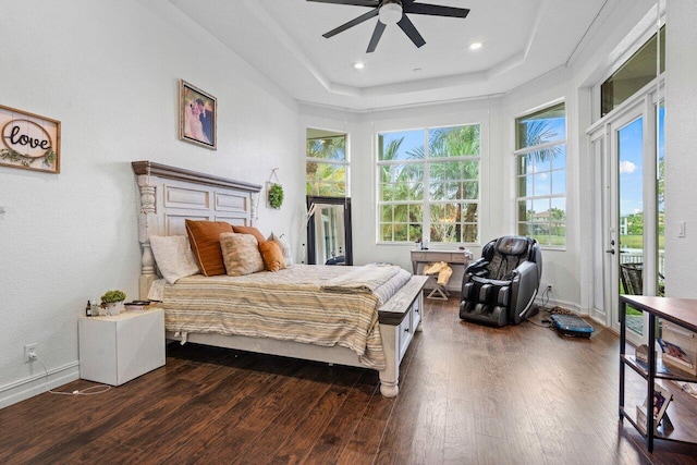 bedroom featuring dark wood-type flooring, access to exterior, a tray ceiling, and ceiling fan