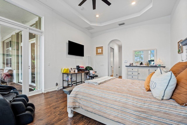 bedroom with ceiling fan, a raised ceiling, access to outside, a high ceiling, and dark hardwood / wood-style floors