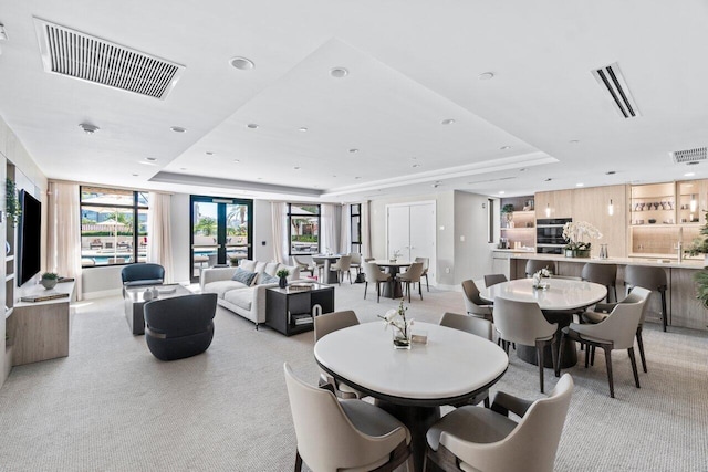 dining space featuring light colored carpet and a tray ceiling