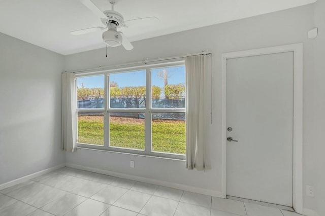 tiled spare room featuring a water view, a healthy amount of sunlight, and ceiling fan