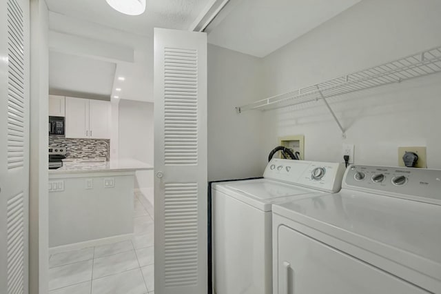 laundry room with washer and clothes dryer and light tile patterned floors