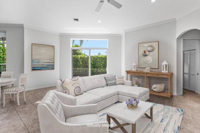 living room featuring light tile patterned floors, a textured ceiling, ornamental molding, and ceiling fan