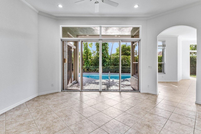 empty room with crown molding, a healthy amount of sunlight, and light tile patterned floors