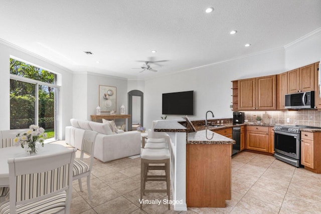 kitchen with a breakfast bar, sink, dark stone countertops, kitchen peninsula, and stainless steel appliances