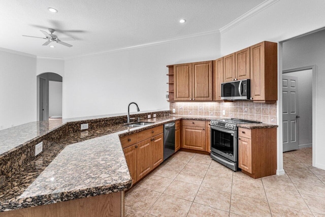 kitchen with light tile patterned floors, sink, appliances with stainless steel finishes, kitchen peninsula, and dark stone counters