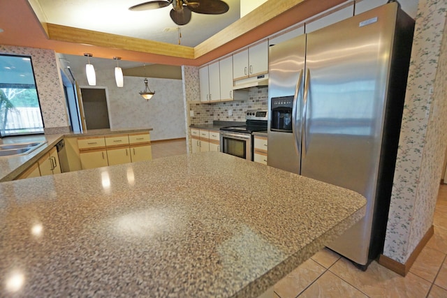 kitchen featuring hanging light fixtures, a tray ceiling, kitchen peninsula, and appliances with stainless steel finishes