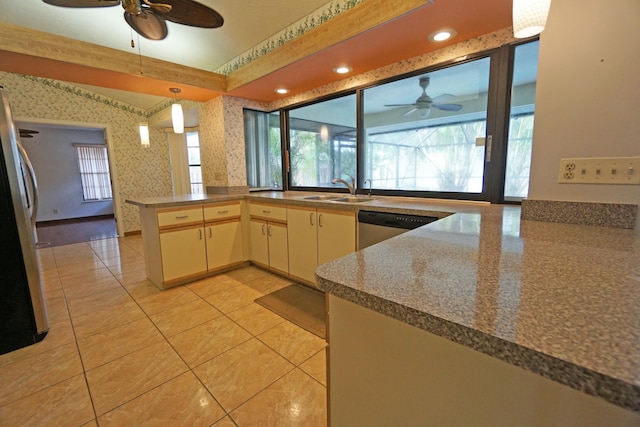 kitchen with appliances with stainless steel finishes, pendant lighting, sink, kitchen peninsula, and cream cabinets