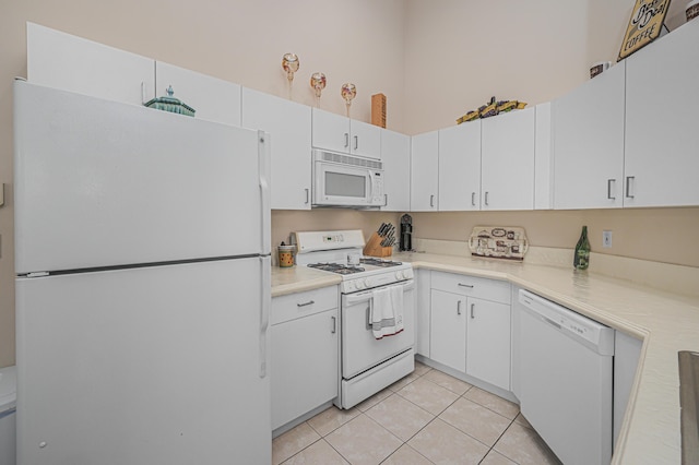 kitchen with light tile patterned floors, white appliances, and white cabinets