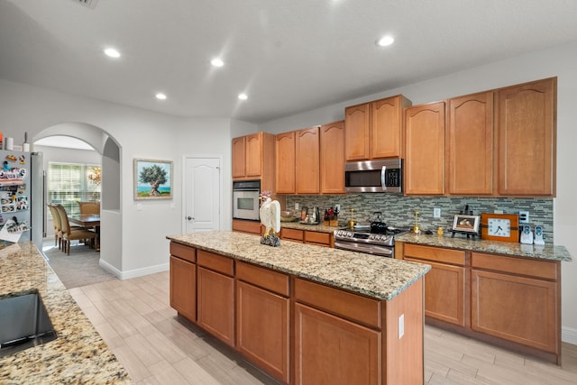 1915 SW Panther Trce, Stuart, FL 34997 - kitchen with appliances with stainless steel finishes, light stone counters, tasteful backsplash, and arched walkways