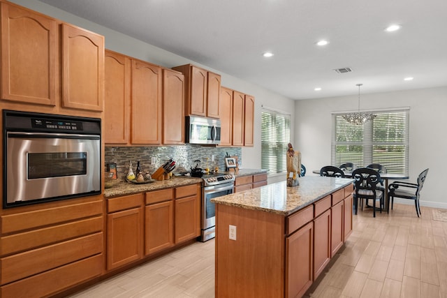 kitchen with pendant lighting, backsplash, light stone countertops, a center island, and stainless steel appliances