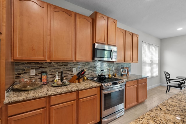 kitchen with light stone countertops, appliances with stainless steel finishes, and tasteful backsplash