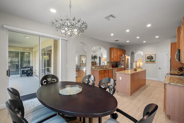 dining area featuring sink, a chandelier, and light hardwood / wood-style flooring