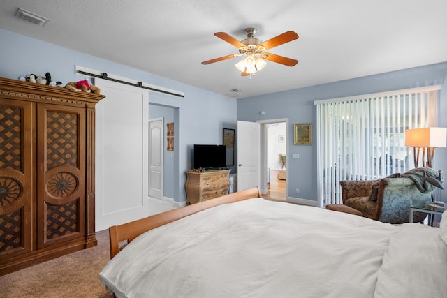 1915 SW Panther Trce, Stuart, FL 34997 - bedroom featuring a barn door, access to exterior, ceiling fan, baseboards, and visible vents