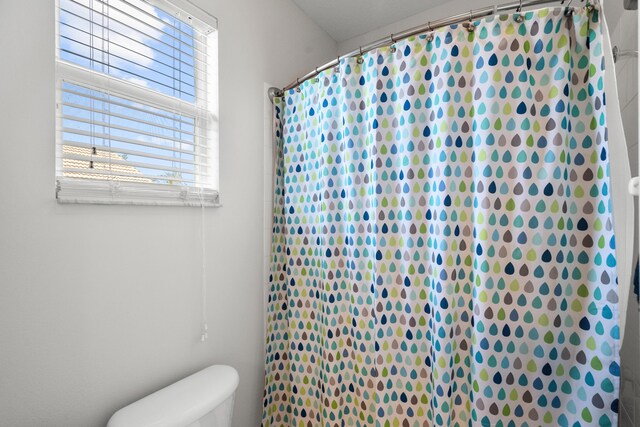 bathroom with a shower with curtain and toilet