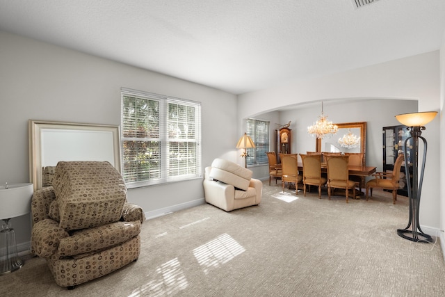 carpeted living room with an inviting chandelier