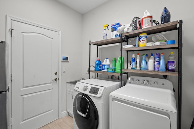 1915 SW Panther Trce, Stuart, FL 34997 - washroom with independent washer and dryer, cabinet space, and light wood-style floors