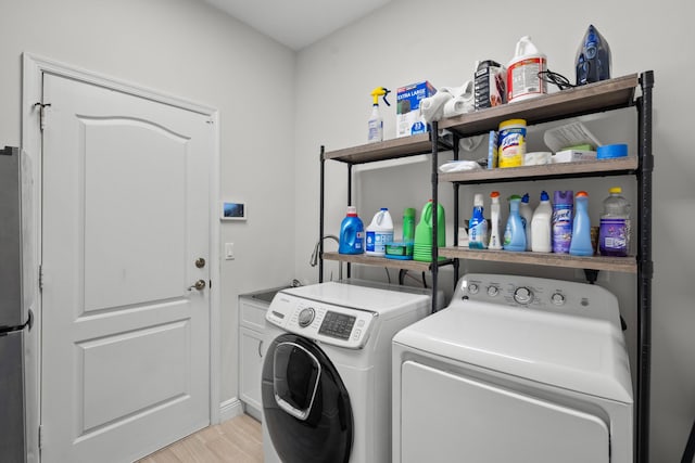 laundry area with cabinets, light hardwood / wood-style flooring, and washing machine and dryer