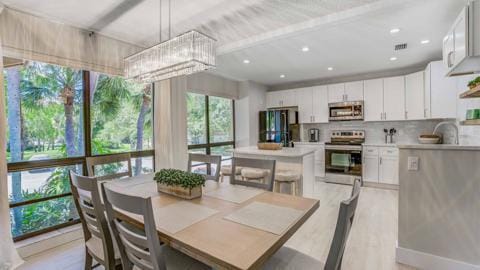 dining room featuring sink, an inviting chandelier, and light hardwood / wood-style floors