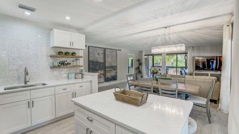 kitchen featuring white cabinets, a kitchen island, decorative backsplash, sink, and light hardwood / wood-style flooring