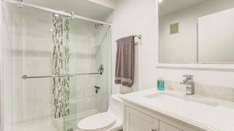 bathroom featuring vanity, toilet, and walk in shower