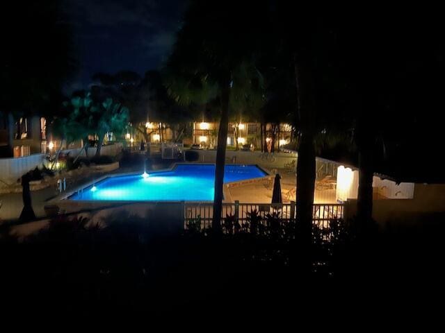 pool at night featuring a community pool