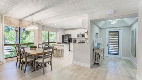 dining space with light hardwood / wood-style floors and a textured ceiling