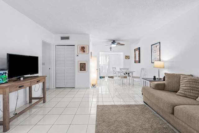 tiled living room with ceiling fan and a textured ceiling