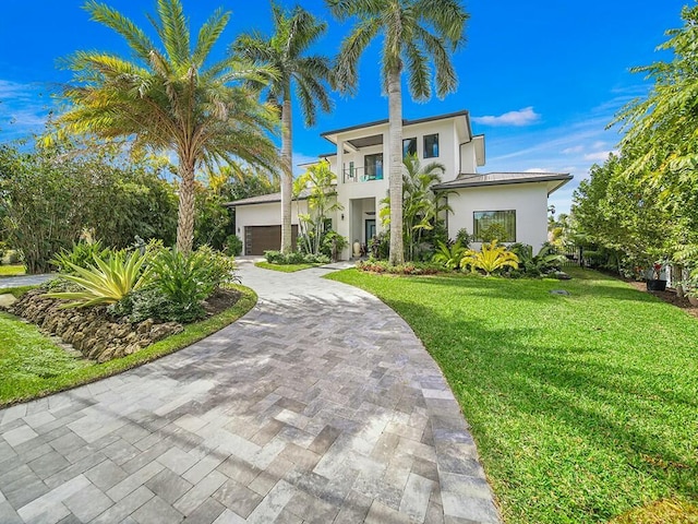 view of front of home featuring a garage, a front yard, and a balcony