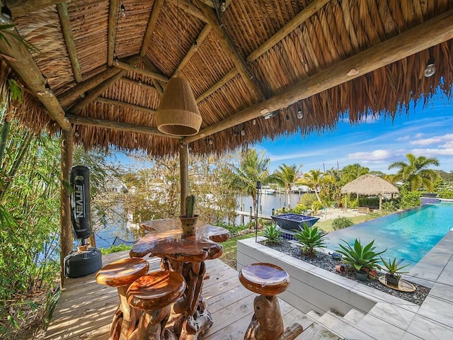 deck with a fenced in pool, a gazebo, and a water view