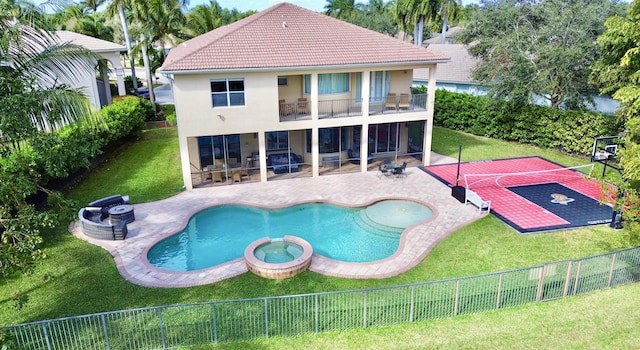 rear view of property with basketball hoop, an in ground hot tub, a lawn, and a balcony