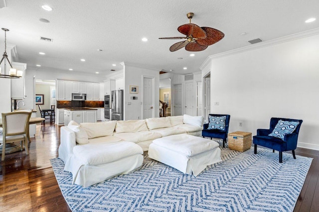 living room featuring ceiling fan with notable chandelier, ornamental molding, dark hardwood / wood-style floors, and a textured ceiling