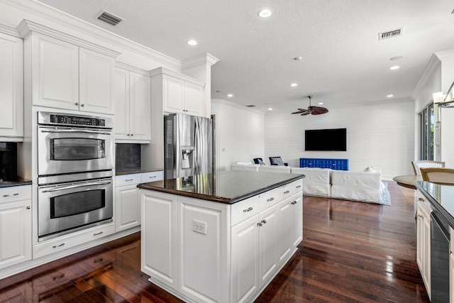 kitchen with white cabinets, a kitchen island, stainless steel appliances, dark hardwood / wood-style floors, and crown molding