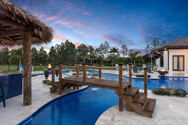 pool at dusk with a jacuzzi and a patio