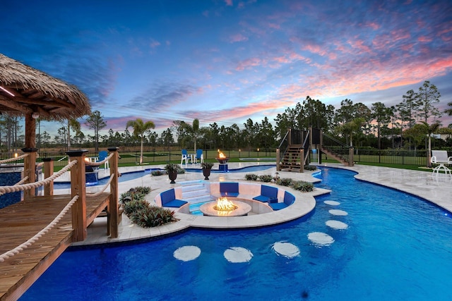 pool at dusk featuring a fire pit