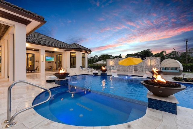 view of pool with a patio area, pool water feature, and an outdoor fire pit