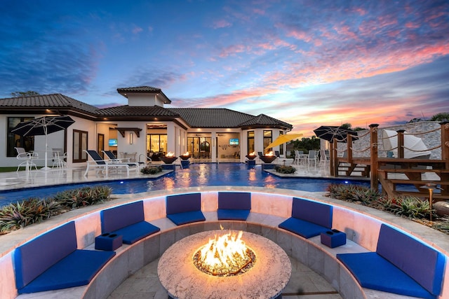 pool at dusk featuring a patio area and an outdoor fire pit