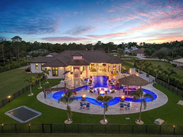 pool at dusk with a patio and a yard