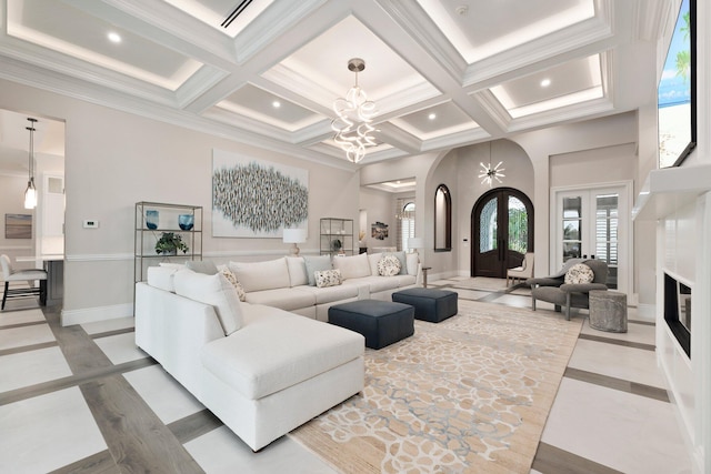 living room with a notable chandelier, beam ceiling, ornamental molding, and french doors