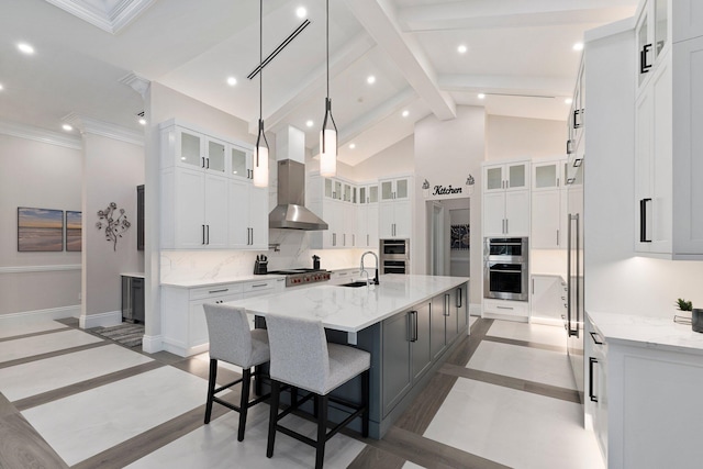 kitchen with sink, white cabinets, decorative backsplash, a center island with sink, and wall chimney exhaust hood