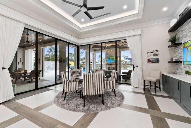 tiled dining area featuring ceiling fan, ornamental molding, and a raised ceiling