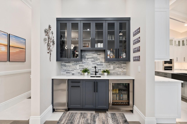 bar featuring tasteful backsplash, stainless steel fridge, beverage cooler, and sink