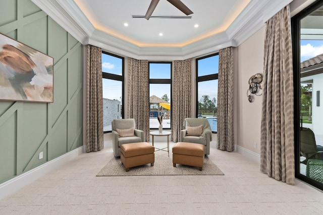 sitting room with ornamental molding and a raised ceiling