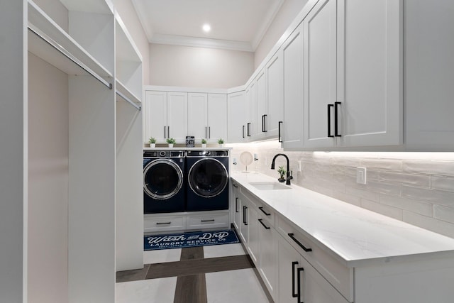 laundry room featuring sink, cabinets, light tile patterned floors, washing machine and clothes dryer, and crown molding