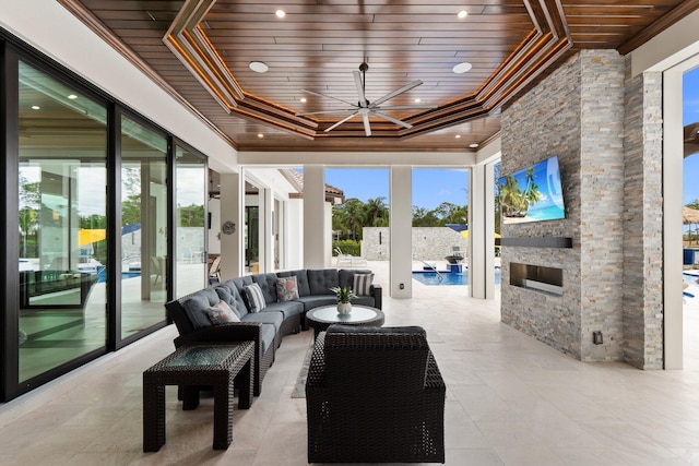 interior space with an outdoor stone fireplace, wood ceiling, and a tray ceiling