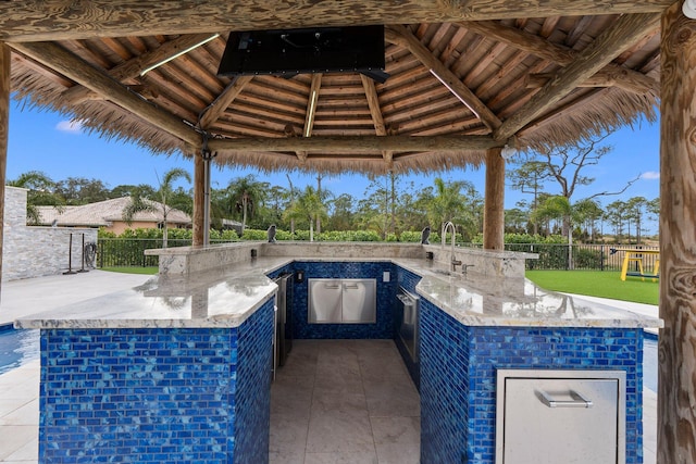 view of patio with exterior kitchen, a gazebo, and an outdoor wet bar