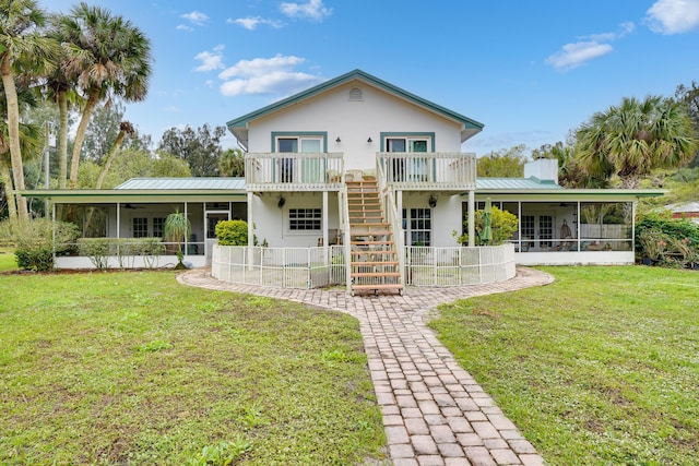 rear view of property with ceiling fan, a yard, and a sunroom