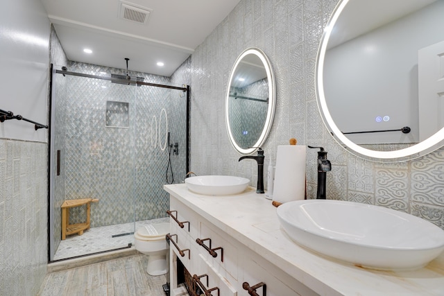 bathroom featuring wood-type flooring, a shower with door, toilet, and vanity