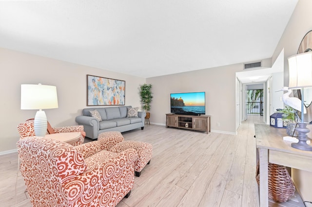 living room with baseboards, visible vents, and light wood finished floors