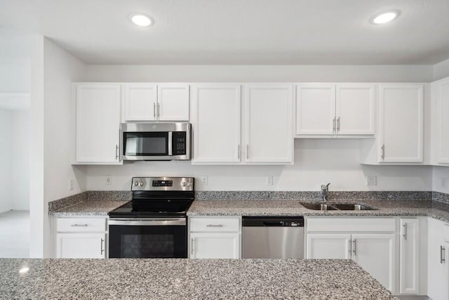 kitchen with light stone countertops, sink, white cabinets, and stainless steel appliances